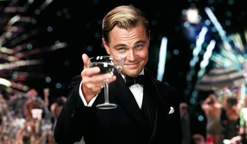 Leonardo Dicaprio holding up a martini glass offering a toast to the viewer